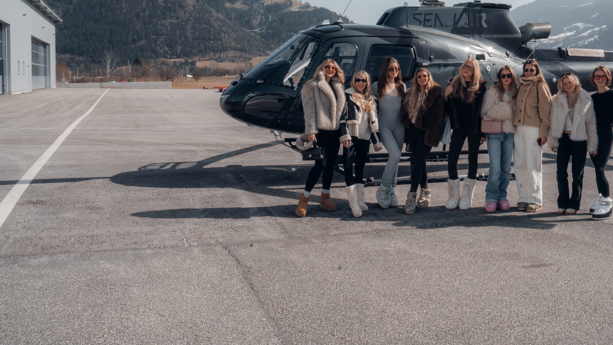 The creators of Janina Reich Agency in front of the helicopter, creator trip Austria 2026